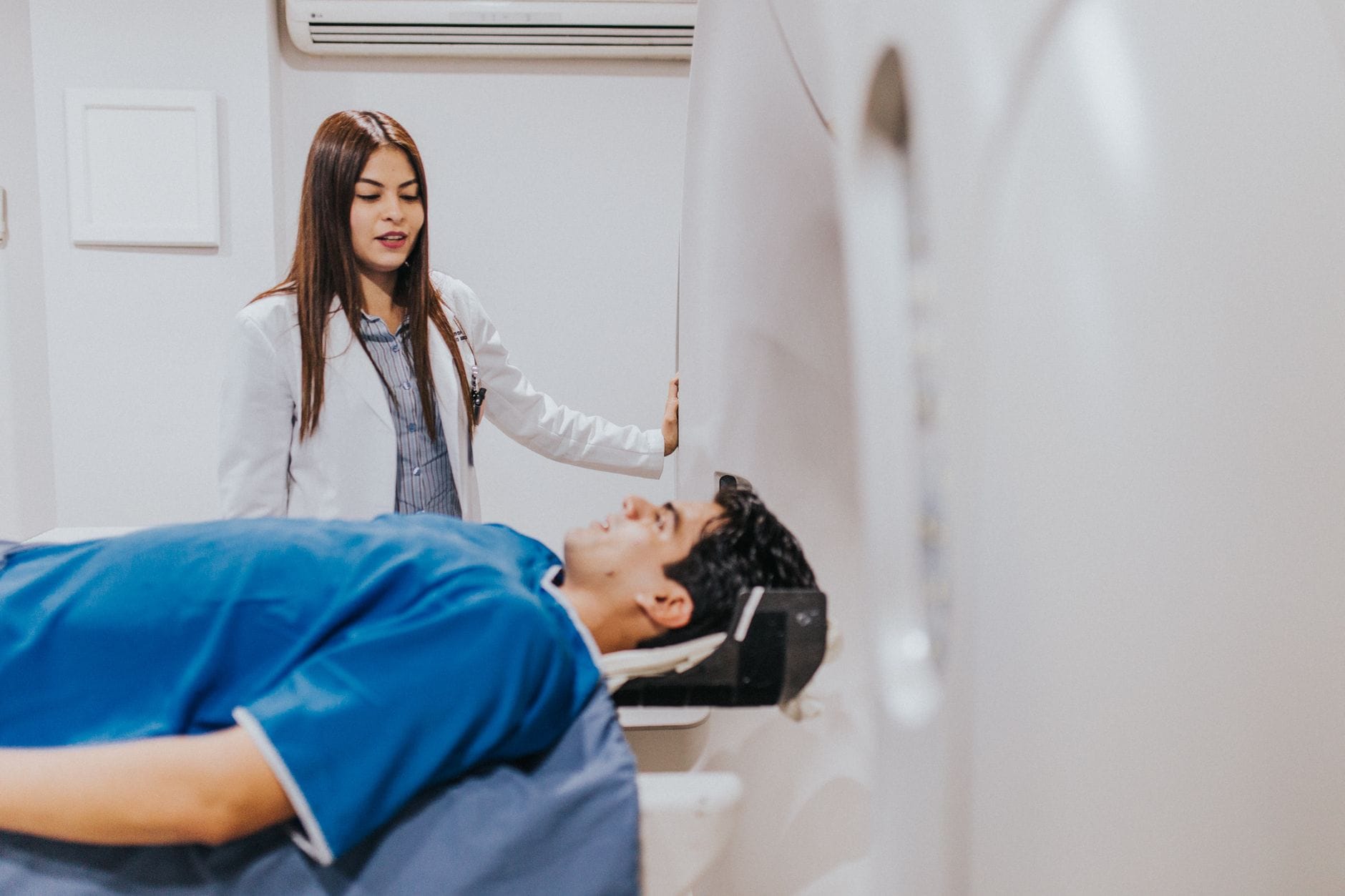 A doctor stands beside a patient in an MRI room, ensuring a smooth examination process.